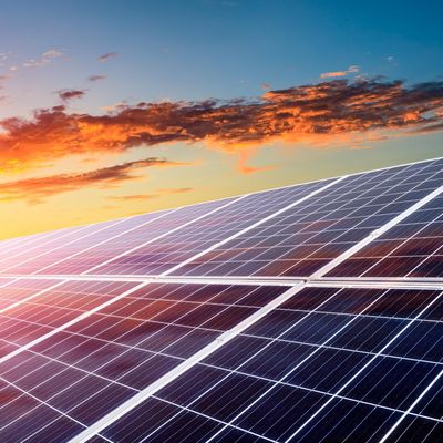 Eine Photovoltaikanlage mit Sonnenuntergang im Hintergrund.
