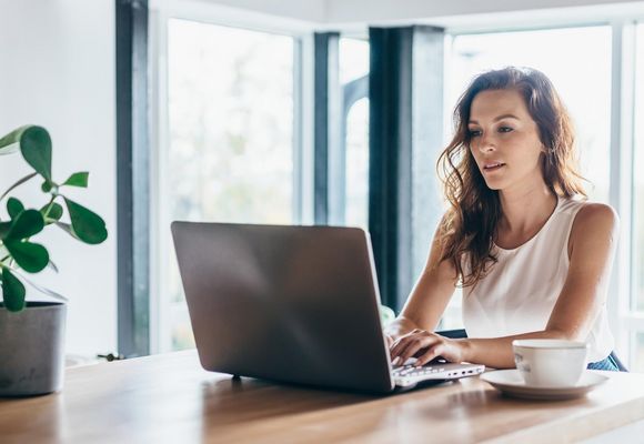 Frau benutzt einen Laptop, während sie zu Hause sitzt.