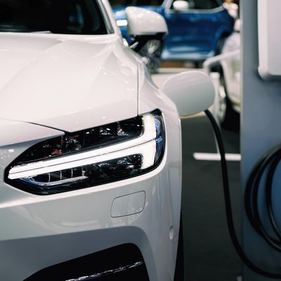 Ein E-Auto von vorne fotografiert, parkt neben einer Ladestation und wird aufgeladeb.