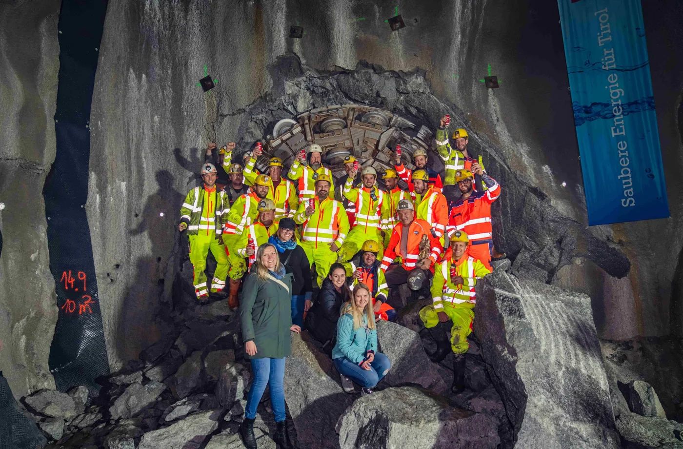 Mineure und Tunnelpatinnen feiern den Durchschlag des Beileitungsstollens nach vier Jahren Bauzeit.